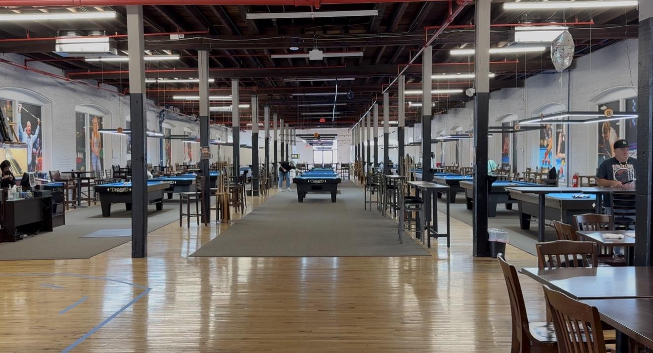 Long aisle of Diamond pool tables under exposed beams