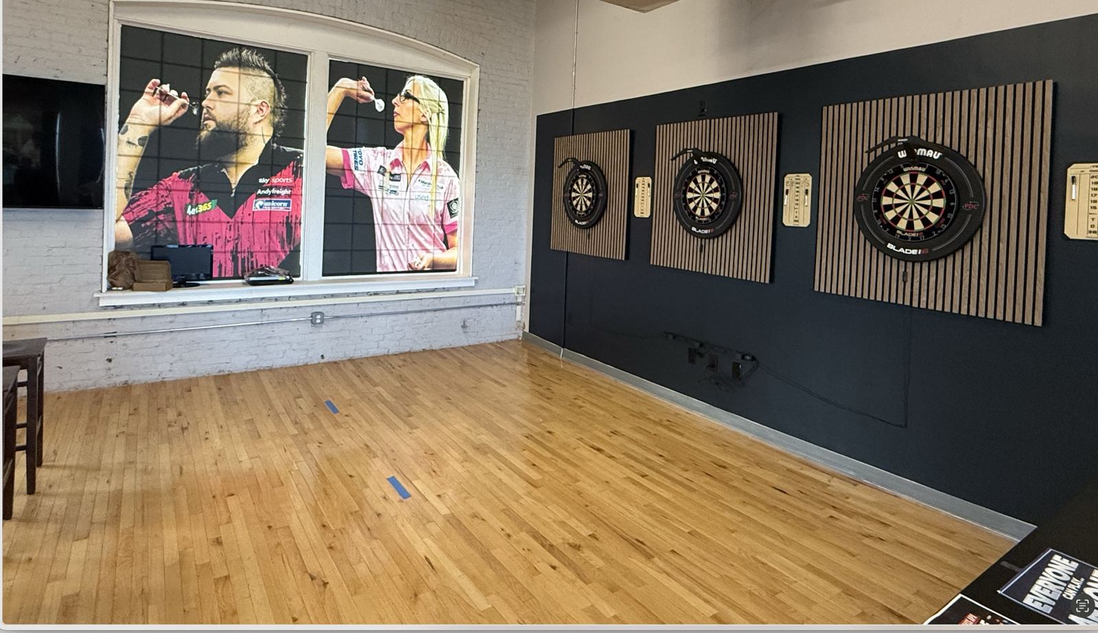 Three dart boards next to pro darts posters